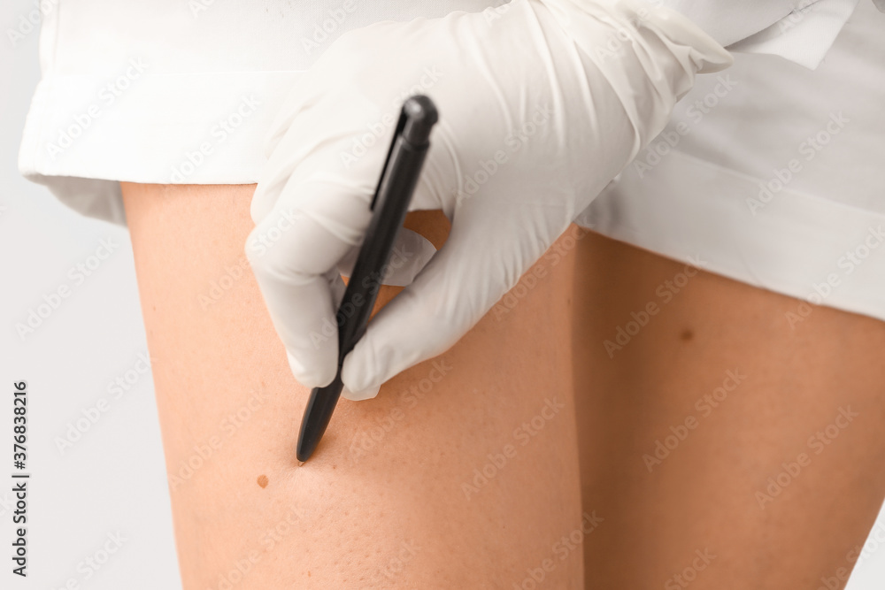 Dermatologist examining patient on grey background, closeup