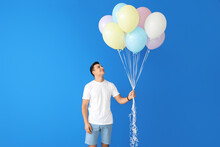 Young Man With Balloons On Color Background