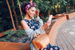© Svetlana Sokolova - Attractive black girl  in trendy hipster cardigan and headband  sitting in the park and making self portrait by  mobile phone .