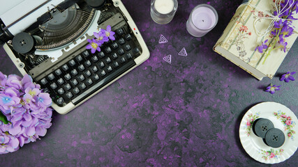 Wall Mural - Purple theme vintage writers desktop workspace with typewriter, lavendar tea, hibiscus flowers and old books on stylish purple textured background. Top view blog hero header creative flat lay.