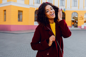 Wall Mural - Mirthful   woman with dark skin posing outdoor. Autumn season. Wearing wool coat and cherry beret.