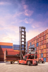 Forklift truck lifting cargo container in shipping yard or dock yard against sunrise sky with cargo container stack in background for transportation import,export and logistic industrial concept