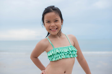 Little  girl playing on the beach on summer holidays. Children in nature with beautiful sea, sand and blue sky. Happy kids on vacations at seaside running in the water. .