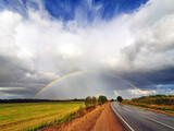 Fototapeta Tęcza - the phenomenon of a hemispherical rainbow in a natural landscape, fields, forests, road. the colorful spectacle of the appearance of a rainbow in late summer, autumn