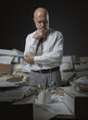 © stokkete - Pensive businessman surrounded by paperwork