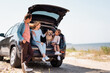 © LIGHTFIELD STUDIOS - Selective focus of family with golden retriever traveling on car on beach