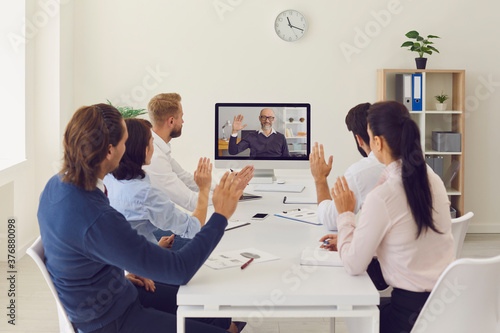 Fototapeta na szkło Company workers sitting in office having online meeting with their CEO using desktop computer