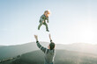 © Serhii - Dad playing with daughter and throws her high in the sky in mountains at the sunset time. Concept of friendly family. Portrait Dad and child enjoying autumn vacation. A place for text, advertising.