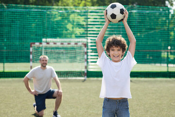 Wall Mural - Little boy posing with soccer ball on football field