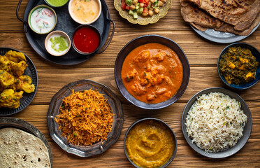 Wall Mural - Assorted Indian home food, different dishes and snacks on wooden rustic table. Homemade Pilaf, butter chicken curry, palak paneer, chicken tikka, dal soup, naan bread, choice of chutney. Top view.