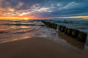 Wall Mural - beautiful sunset on the baltic sea, waves washing the old wooden breakwaters