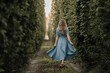 © Полина Древаль - a girl in a blue dress runs between rows of hop plantations