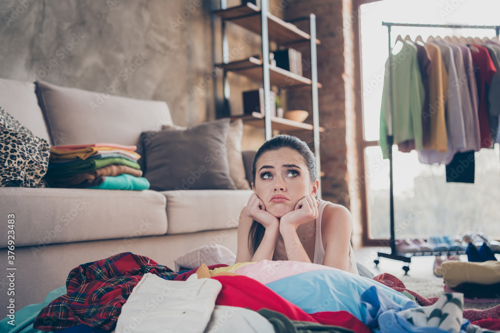Photo of pretty stressed crying lady stay home quarantine lying many clothes heap stack floor wardrobe stuff pick select date look outfit nothing to wear concept living room indoors - obrazy, fototapety, plakaty 