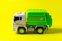 The Toy Garbage Truck White-green With A Yellow Background. Children's Toy Car With Buttons.