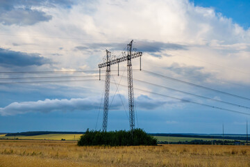 High voltage power line in a farm field. Scenic sky with clouds in the background