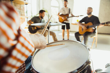 Close up hands playing. Musician band jamming together in art workplace with instruments. Caucasian men and women, musicians, playing and singing together. Concept of music, hobby, emotions, art