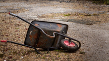 Discarded Rusty Wheelbarrow And A Neglected Garden