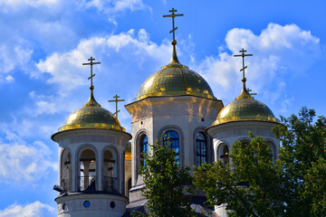 Golden domes of the temple against the blue sky and clouds