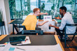 © BullRun - Cheerful office worker showing charts to puzzled black colleague