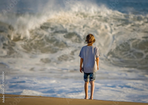 Fotomural Boy standing looking at high surf at Newport Beach CA