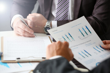 Male arm in suit and tie fill form clipped pad with silver pen closeup. Sign gesture read pact sale agent bank job make note loan credit mortgage investment finance executive chief legal teamwork law