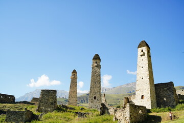 Old stone towers in green mountainous terrain. Ancient stone buildings of old town located on green in summer day