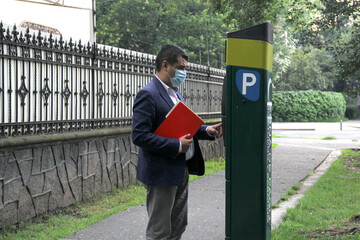 
Latino adult man with protection mask and red folder, paying public parking on the street, new normal covid-19