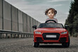 © Cavan Images - Girl riding toy car on road