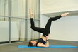 © Petr Smagin - woman doing pilates or yoga exercises in gym