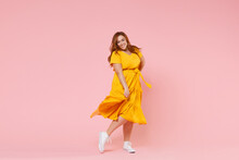 Full Length Portrait Of Smiling Beautiful Charming Young Redhead Plus Size Body Positive Female Woman Girl 20s In Yellow Dress Posing Looking Camera Isolated On Pastel Pink Color Background Studio.