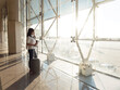 © Cavan Images - young woman with suitcase talking on phone while waiting for flight