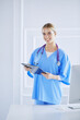 © lenets_tan - Smiling female doctor with a folder in uniform standing