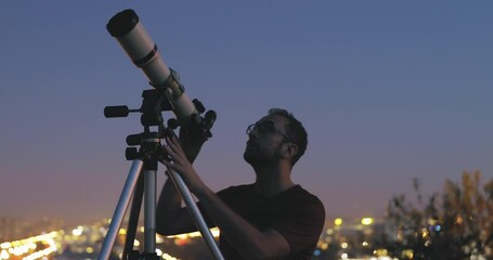 Wall Mural - astronomer with a telescope watching at the stars and moon with blurred city lights in the backgroun