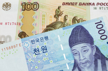 A macro image of a Russian one hundred ruble note paired up with a blue and white one thousand won bill from Korea.  Shot close up in macro.