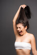 © LIGHTFIELD STUDIOS - upset brunette woman holding damaged hair and yelling isolated on black