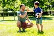 © Syda Productions - family, fatherhood and people concept - happy father and little son with soccer ball making high five gesture at summer park