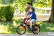 © Syda Productions - family, fatherhood and leisure concept - happy father teaching little son to ride bicycle at park