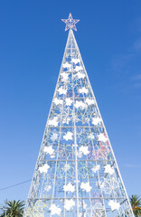 Large metal Christmas tree outside with a clear blue sky