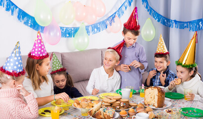 Wall Mural - Playful children enjoying friend birthday during festive dinner.