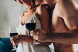 Cropped view of muscular man holding glass of wine and kissing seductive woman at home
