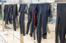 Surf Suits Dry In The Sun On A Glass Fence