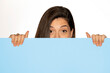 young beautiful woman peeking behind a blue empty board