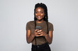© F8  \ Suport Ukraine - Happy young african woman casually dressed holding mobile phone standing isolated over gray background