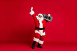 © deagreez - Full length photo of retired old man white beard careless raise hand hold listen retro radio tape wear x-mas santa costume gloves coat belt sunglass cap boot isolated red color background