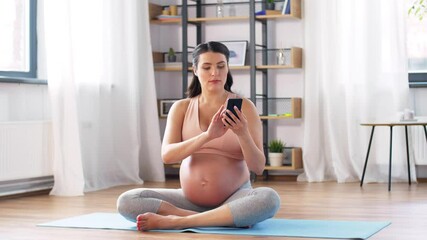 Wall Mural - pregnancy, sport and people concept - happy pregnant woman with smartphone doing yoga breathing exercise at home