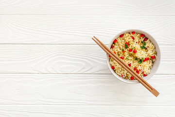 Instant noodle with pepper,peas and greens. White wooden background top view copy space