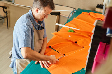 A man preparing, measuring and cutting upholstery fabric on a workbench