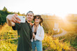 © Serhii - Happy young couple walks on the old railway bridge against the backdrop of the sunrise and smiles, wearing stylish summer clothes. Young tourists go holding hands on a viaduct in the mountains