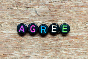 Wall Mural - Black bead with color letter in word agree on wood background