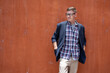 © Pituk - Portrait of young man leaning against brick wall outdoors.